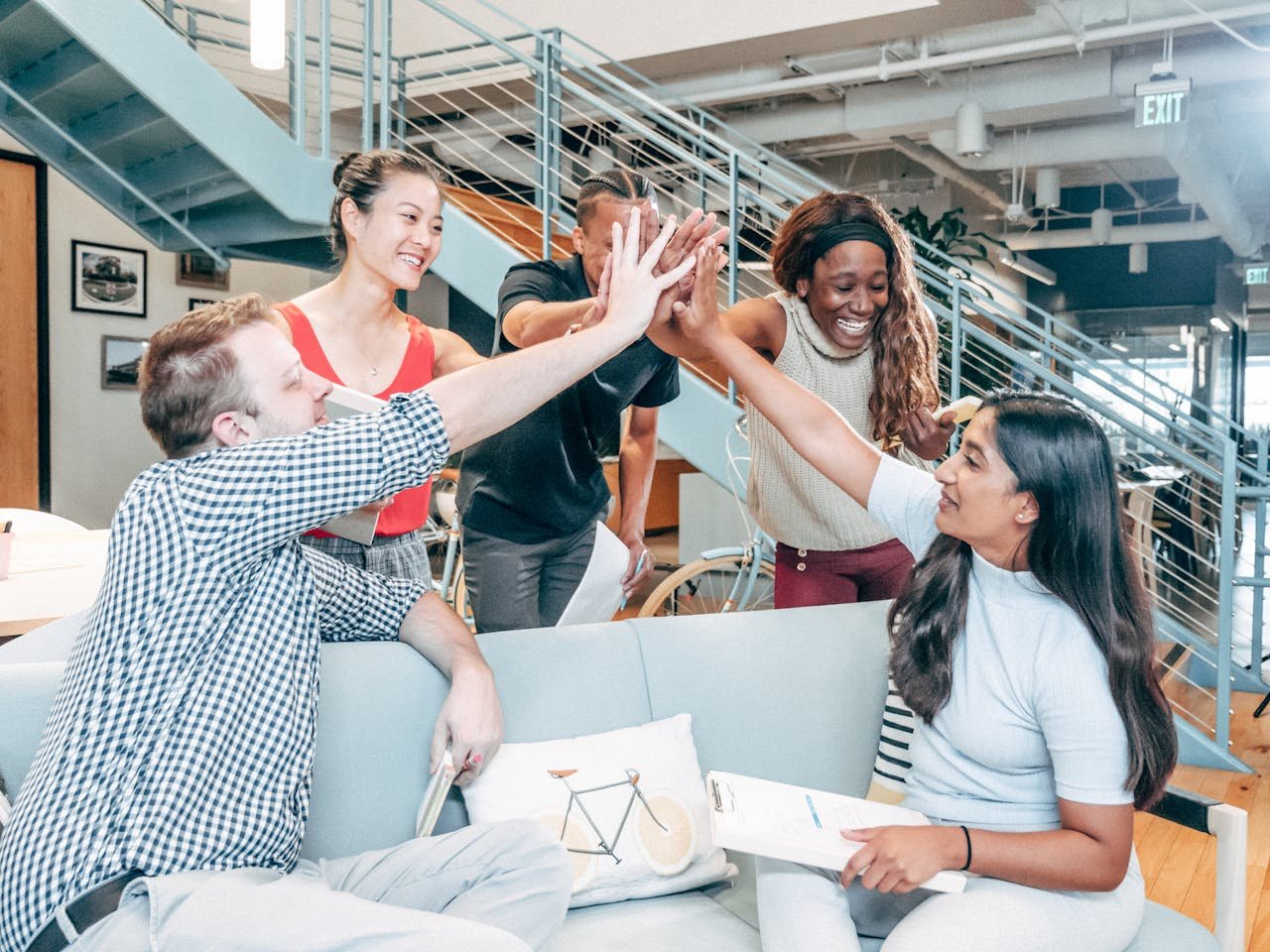 why-choose-us A diverse team celebrates success with a high-five in a modern office setting.